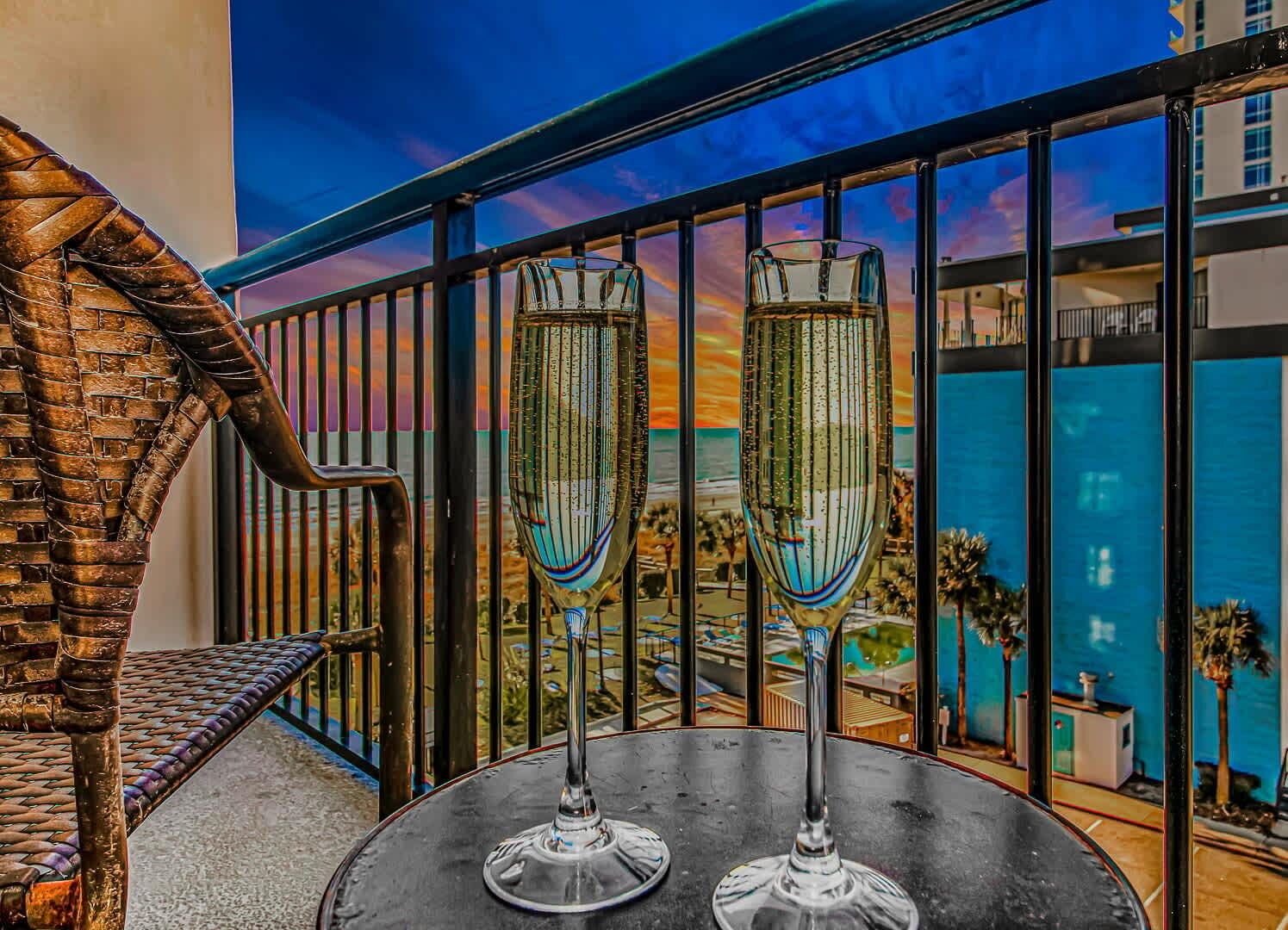 Un balcone con due flute di champagne, una ringhiera in metallo e vista su spiaggia ed edifici.