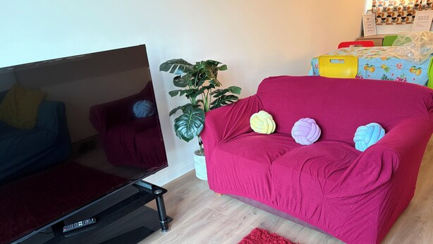 A living room with a red sofa, a television, a potted plant, and a red rug. - Ivy Veil
A home away from home (Witham)