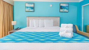 Hotellihuone, jossa on sänky, yöpöytä, lamppu ja kaksi taulua seinällä.