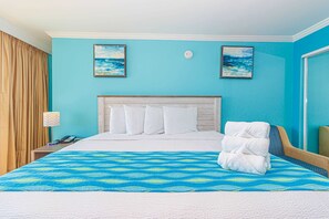 A hotel room with a bed, a nightstand, a lamp, and two paintings on the wall. - Caravelle 515 Studio (Myrtle Beach)