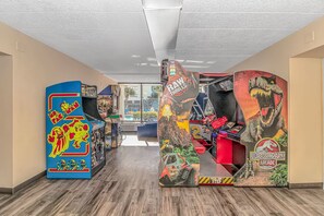 A hallway with arcade machines, including Pac-Man and Jurassic Park Arcade games. - Caravelle 515 Studio (Myrtle Beach)