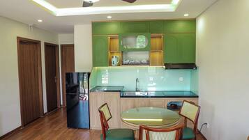 A compact kitchen with a built-in refrigerator, a sink, and a dining area with two chairs.