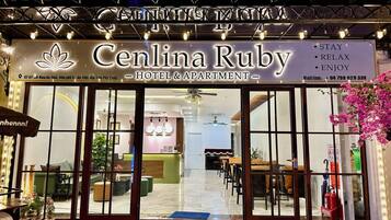 The exterior of the Cenlina Ruby Hotel & Apartment with a reception area visible through the glass doors.
