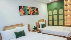 Una habitació d'hotel amb dos llits, una paret verda i un quadre abstracte i colorit.