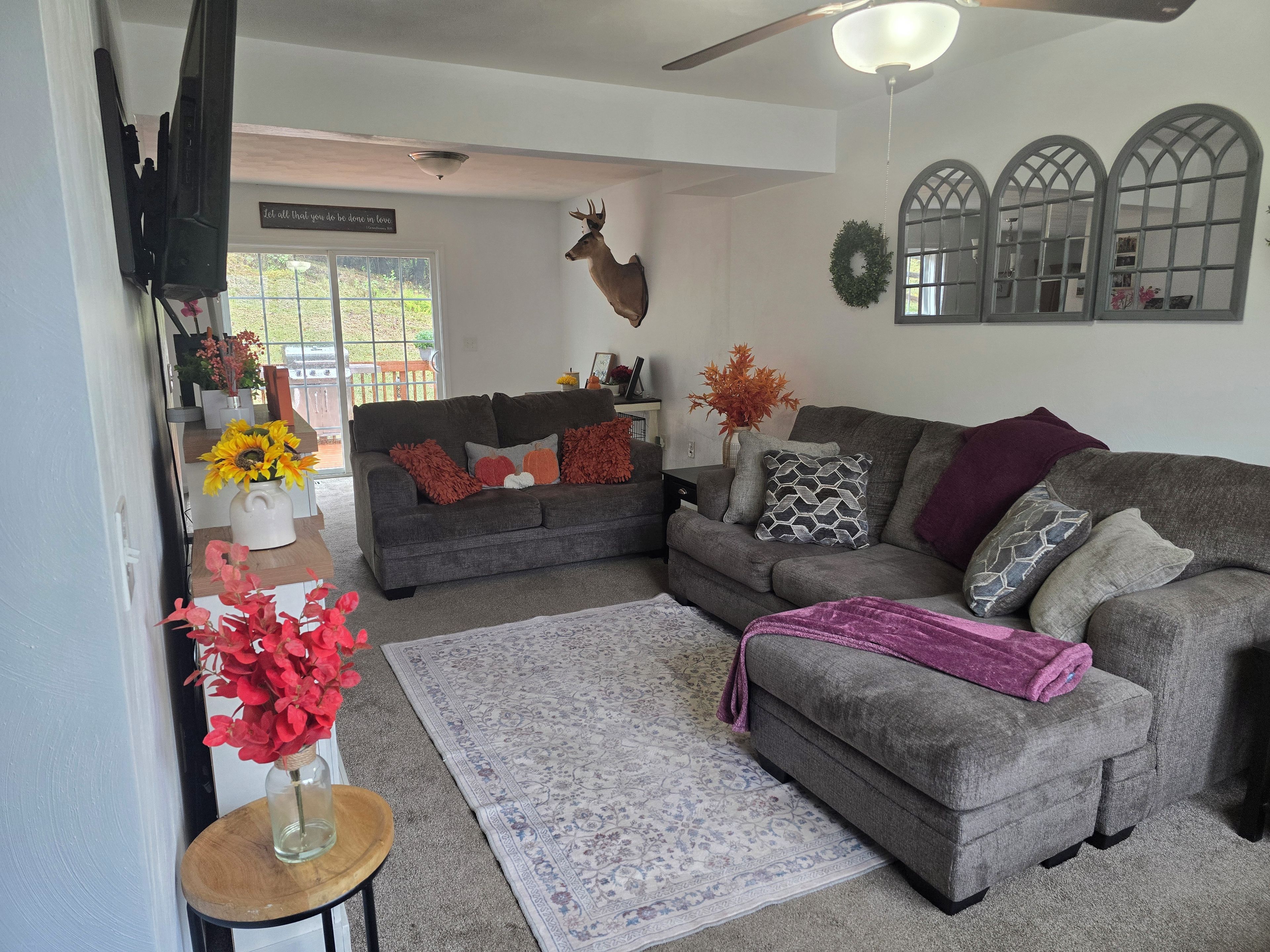 A living room with a grey sofa, a wooden coffee table, and a decorative deer head.