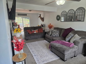 A living room with a grey sofa, a wooden coffee table, and a decorative deer head.