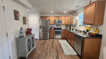 A modern kitchen with wooden cabinets, stainless steel appliances, and a grey cabinet with decorative items.