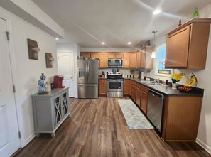 A modern kitchen with wooden cabinets, stainless steel appliances, and a grey cabinet with decorative items.