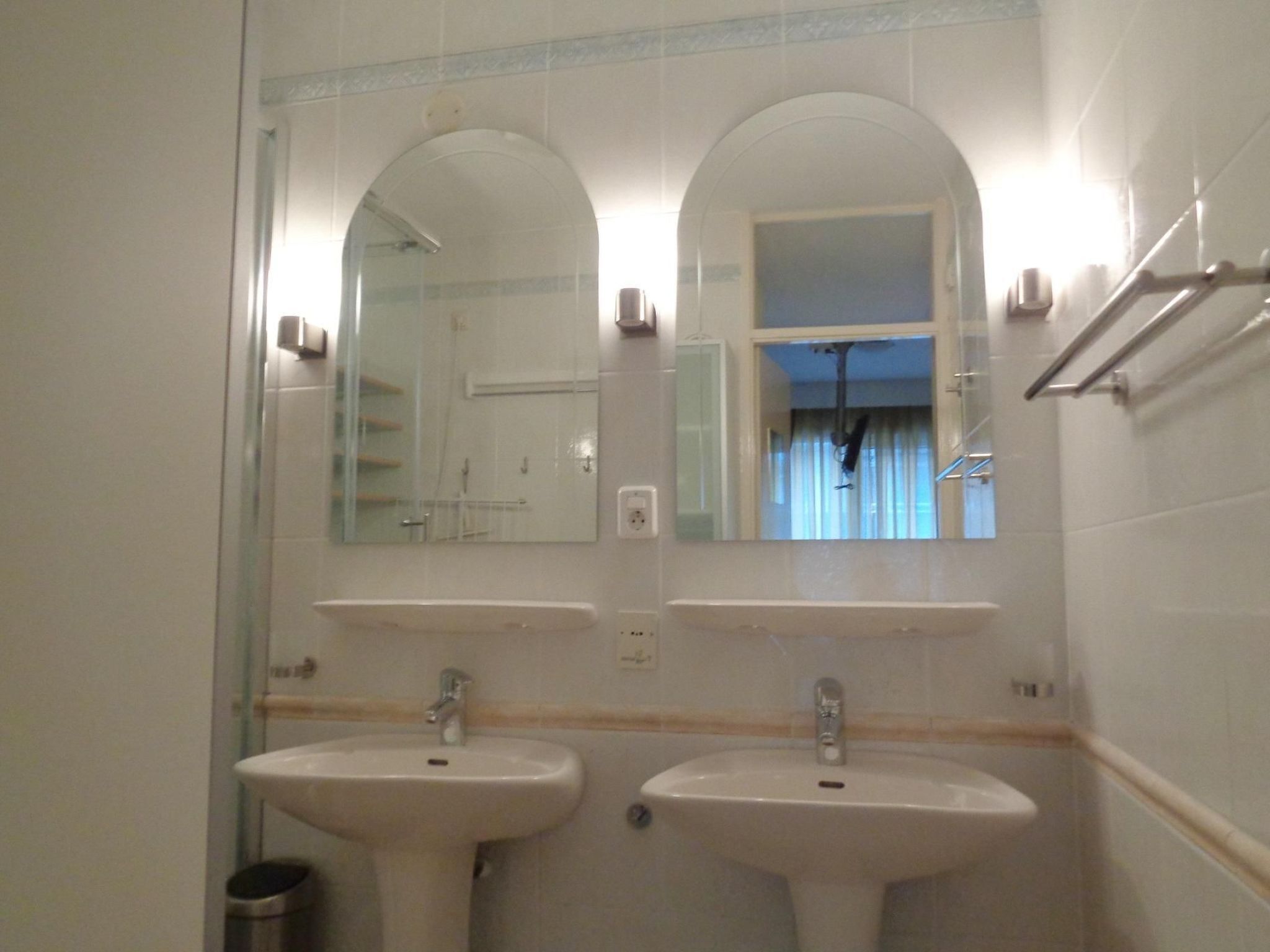 Une salle de bain avec deux lavabos, un miroir et une fenêtre.