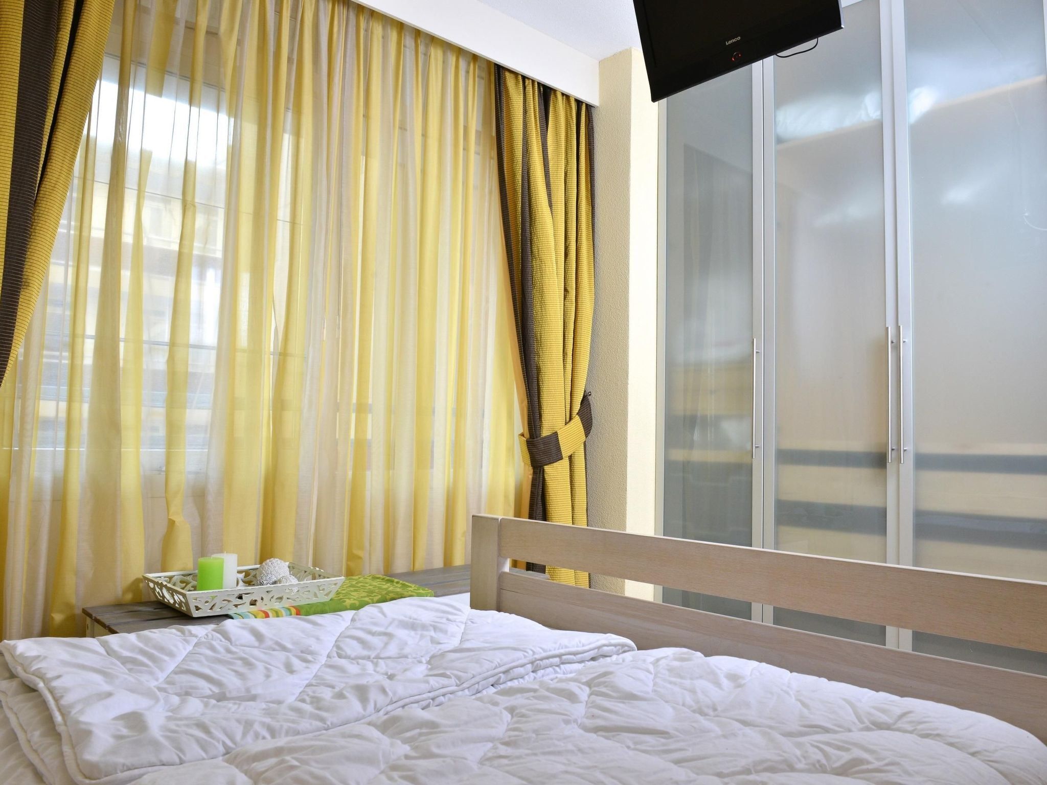 Una habitación de hotel con cama, cortinas, televisor y puerta corrediza.
