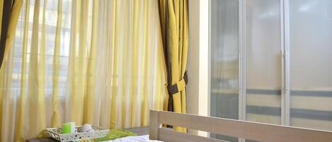 Een hotelkamer met een bed, gordijnen, een televisie en een schuifdeur.