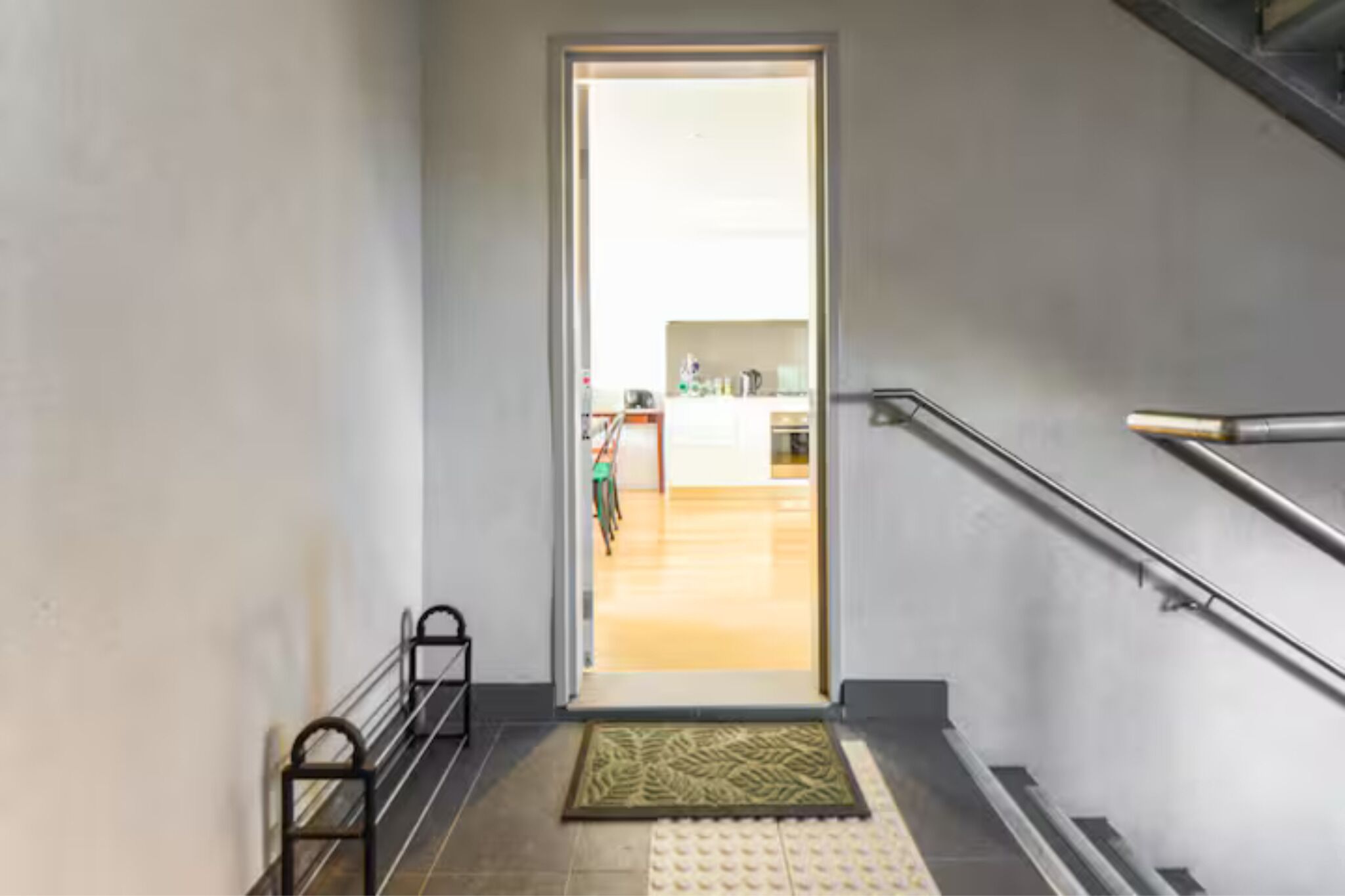 A staircase leading to a bright room with a kitchen in the background.