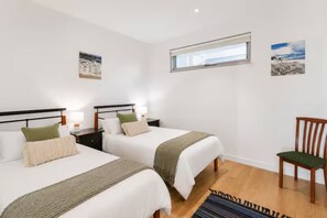 A hotel room with two beds, a window, and a chair.