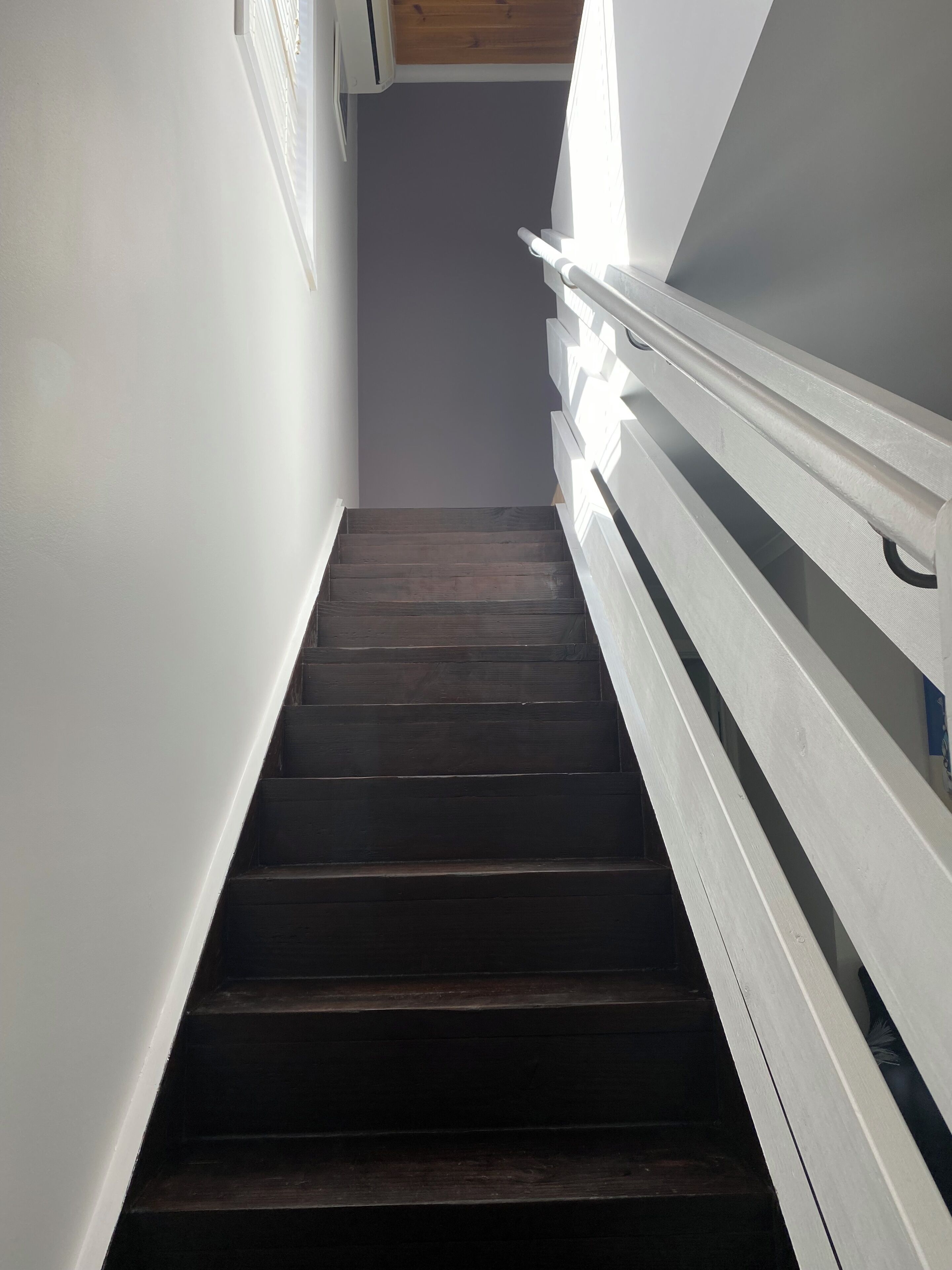 A staircase with dark wooden steps and white railings, leading to a higher floor.