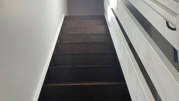 A staircase with dark wooden steps and white railings, leading to a higher floor.