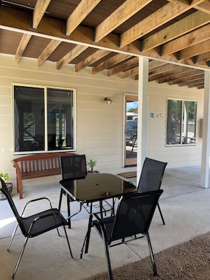 An outdoor patio with a wooden ceiling, a table with chairs, a bench, and large windows. - Coastal Retreat 400 Metres to Beach (Cowes)