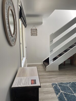 Un interior modern amb una escala, una taula de fusta amb un menú i un mirall decoratiu.