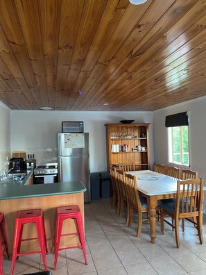 A kitchen with wooden ceiling, a dining table with chairs, and a refrigerator. - Coastal Retreat 400 Metres to Beach (Cowes)