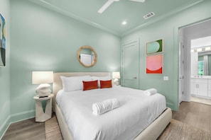 Ein Schlafzimmer mit einem Bett, Nachttischlampen, einem runden Spiegel und Kunstwerken an der Wand.