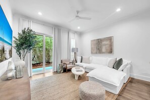 Ein modernes Wohnzimmer mit einem weißen Sofa, einem Couchtisch und einem Deckenventilator.