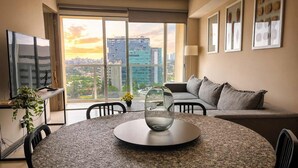 A modern living room with a round table, a sofa, and a large window offering a city view. - Modern Apartment in ParkLife |City View (Guadalajara)