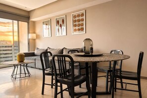 A modern dining area with a round table, black chairs, a sofa, and a vase on a small table. - Modern Apartment in ParkLife |City View (Guadalajara)