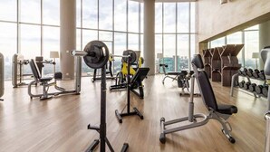 A gym with various exercise equipment, large windows, and a city view. - Modern Apartment in ParkLife |City View (Guadalajara)