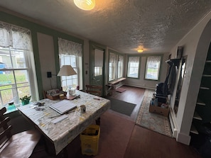 A room with a table, chairs, a lamp, a window, and a door. - Riverview Cottage, a quaint downtown home with River and Park views (Millinocket)