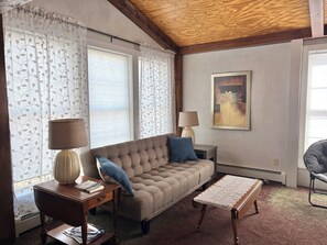 Ein Wohnzimmer mit einer Couch, zwei Lampen, einem Couchtisch, einem Sessel und einem Bild an der Wand.