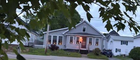 A residential house with a front porch, a driveway, and a parked car.