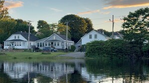 A residential area with houses, a calm body of water, and a clear sky. - Riverview Cottage, a quaint downtown home with River and Park views (Millinocket)