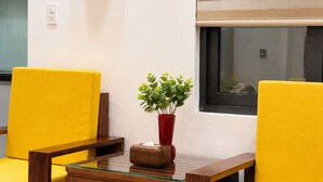 A room with two yellow chairs, a small table, a red vase with a plant, and a window with a view. - Han House's Apartment 1 (Da Nang)
