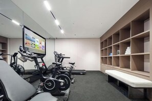 Une salle de sport équipée de vélos d’appartement, d’un tapis de course et d’un banc de musculation.