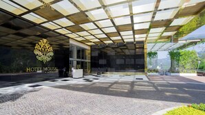 A hotel entrance with a glass canopy, a reception desk, and a logo. - Hotel Mousai Puerto Vallarta-Studio Suite W/ Private hot tub, Oceanview & Butler (Puerto Vallarta)
