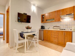 A compact kitchen with wooden cabinets, a built-in oven, and a flat-screen TV. - Villa Delia by Interhome (Medulin)