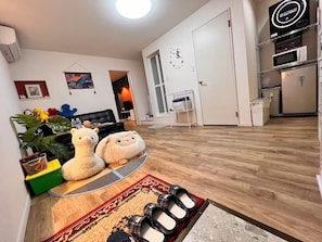 A living room with a sofa, two stuffed animals, a coffee table, and a rug. - Direct KIX Train & 1 min Walk to Station - Vibrant Osaka 2BR Apt w/ AC (大阪市)