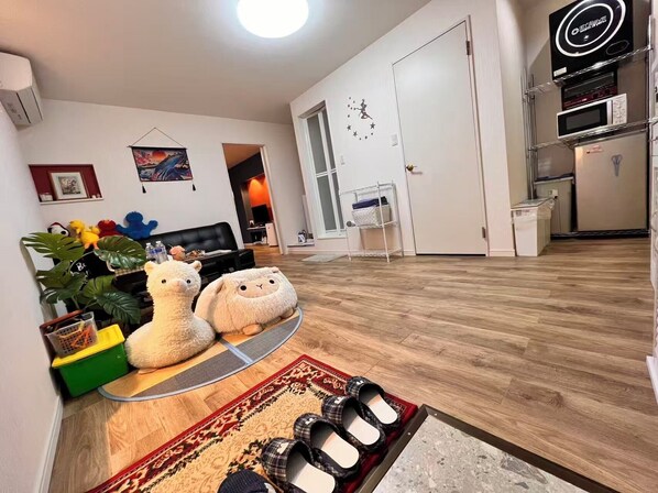 En stue med en sofa, to bamser, et sofabord og et tæppe.