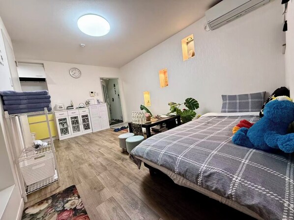 A bedroom with a bed, a desk, a wardrobe, and a bathroom visible in the background.