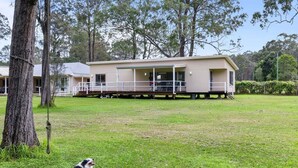 A single-story building with a covered outdoor area, surrounded by trees and grass. - Native Retreat - Tranquil Seaham Escape (Port Stephens)