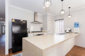 A modern kitchen with a built-in refrigerator, stove, and sink. - Spacious 4BR Family Home • Pool with Spa & BBQ (Byford)