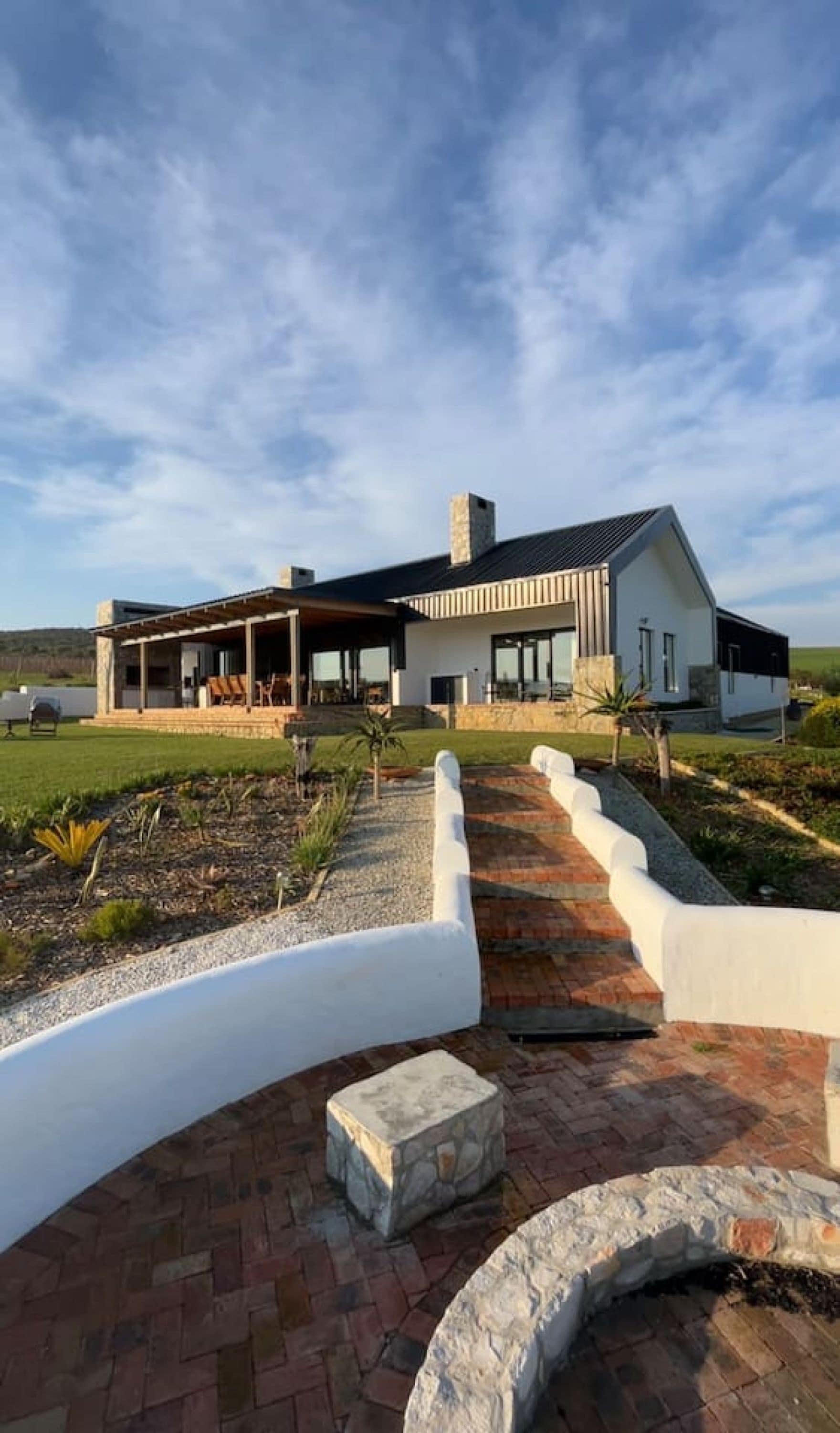 Una casa moderna con un porche cubierto, un camino de piedra y un jardín ajardinado.