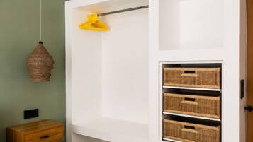 A bedroom with a bed, a bedside table, a hanging light, and built-in storage with baskets.