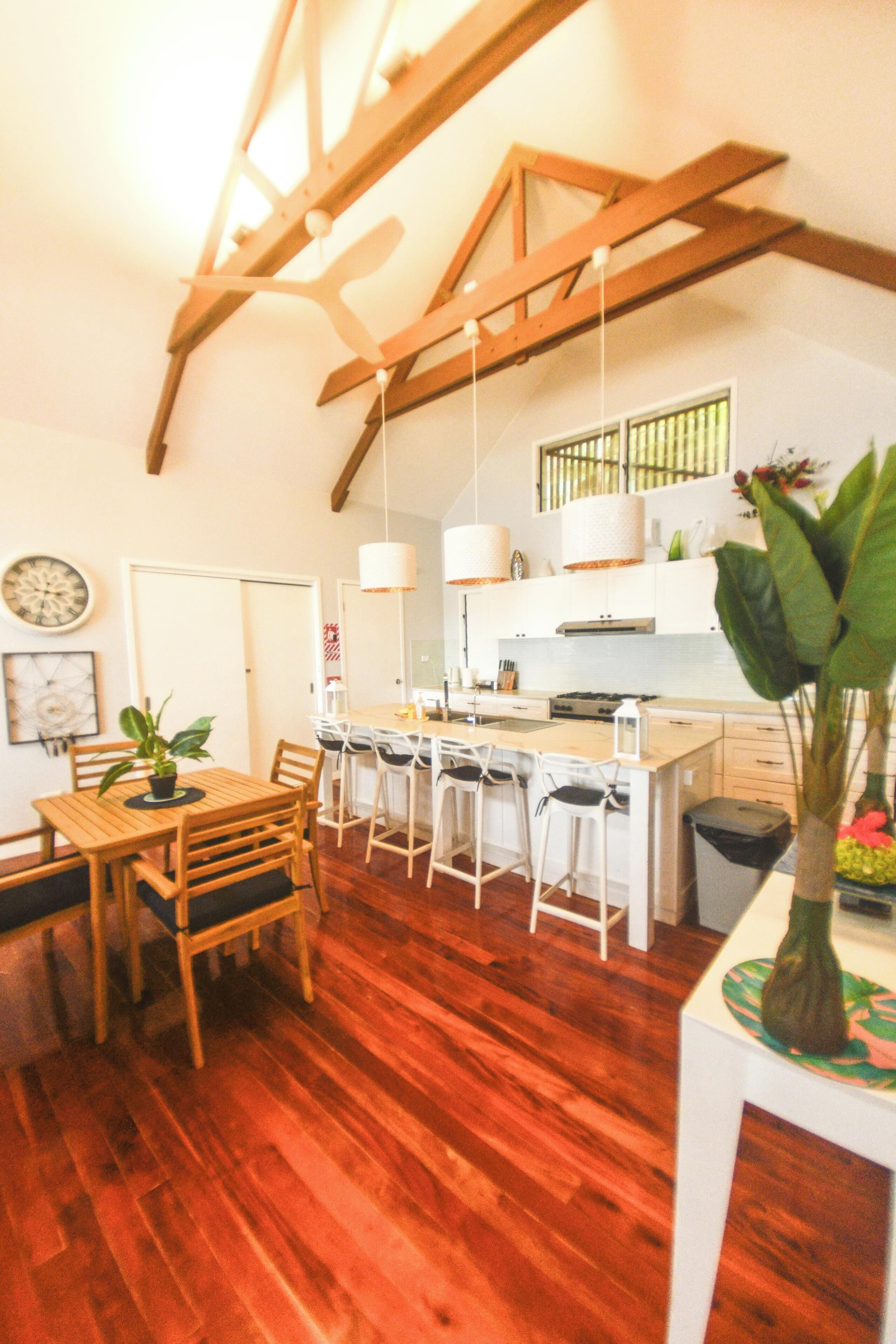A modern kitchen with white cabinets, a wooden dining table, and bar stools.