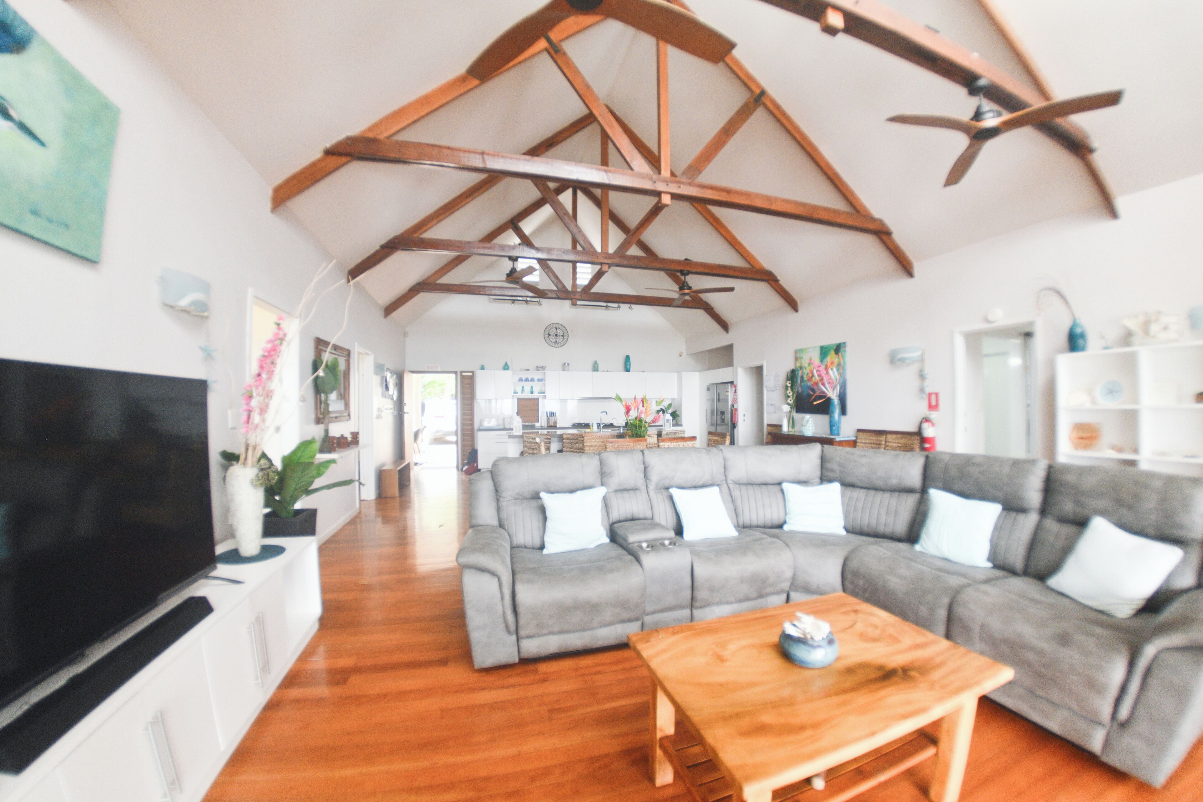 A spacious living room with a large grey sectional sofa, a wooden coffee table, and a flat-screen TV.