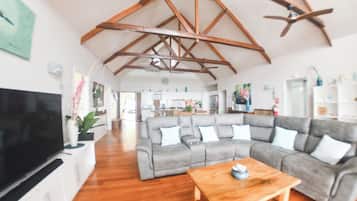 A spacious living room with a large grey sectional sofa, a wooden coffee table, and a flat-screen TV.