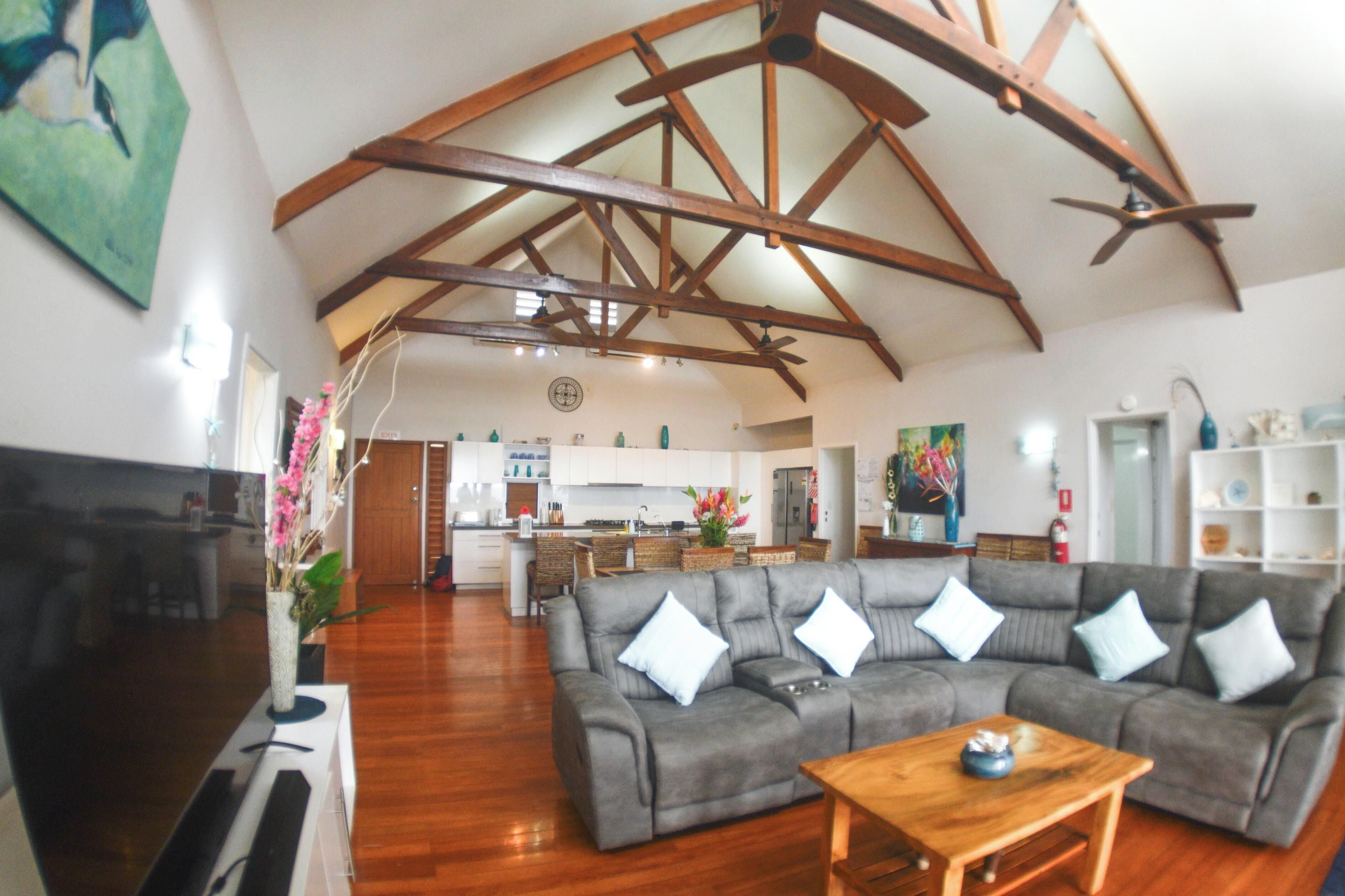 A spacious living room with a grey sectional sofa, wooden flooring, and a ceiling fan.
