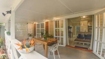 An outdoor dining area with a wooden table and chairs, surrounded by potted plants.