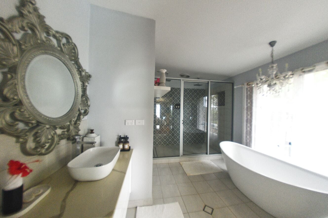 Une salle de bain dotée d’un grand miroir, d’une baignoire sur pieds et d’une douche à parois de verre.