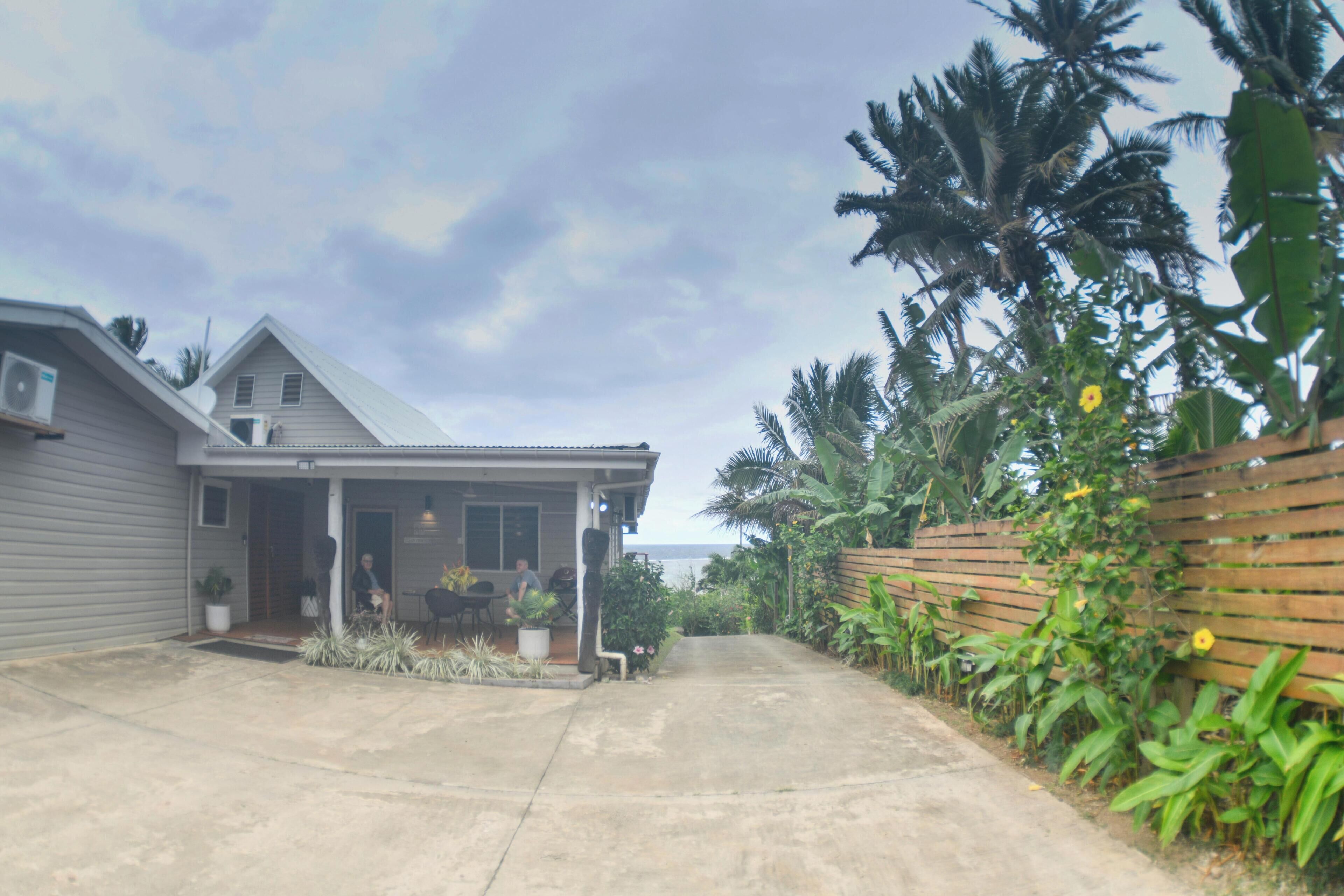 A residential property with a paved driveway, a covered porch, and a wooden fence.