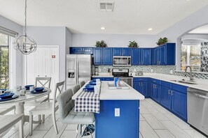 A modern kitchen with blue cabinets, stainless steel appliances, and a central island. - Luxury 6 Bedroom Pool Home Near Disney (Kissimmee)
